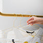Hand präsentiert goldene Kleiderbügel, die auf einer Garderobenstange hängen