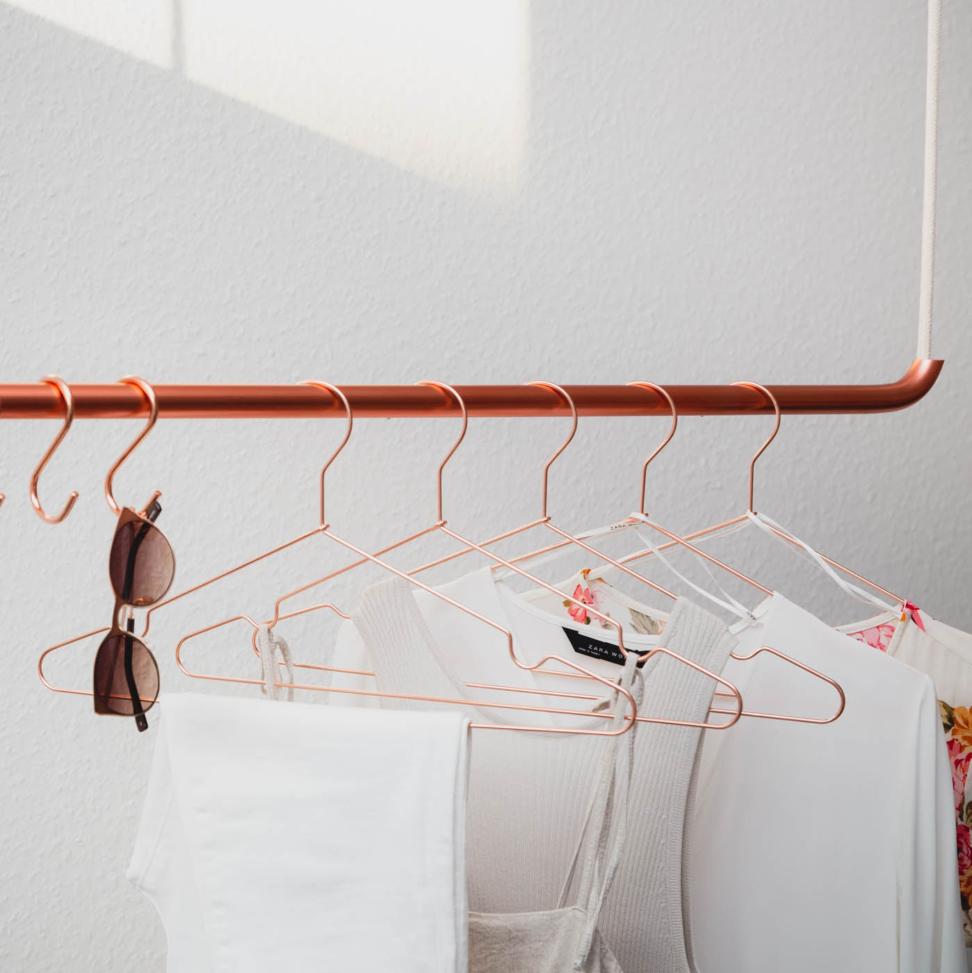 Kupferfarbenden Kleiderbügel hängen leuchtend an Kleiderstange von der Decke