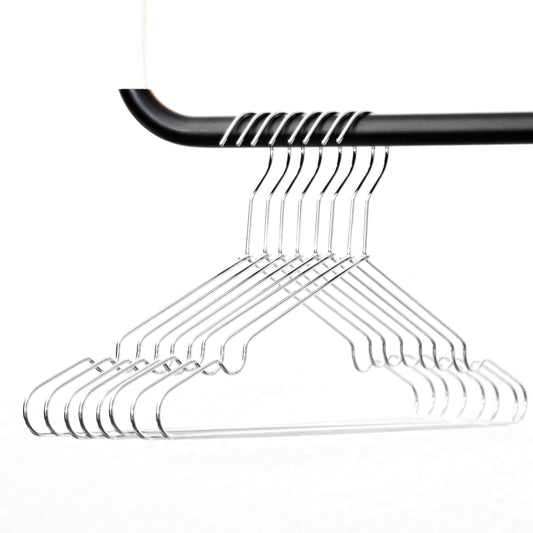 Eine Reihe von Rod & Knot Kleiderbügeln aus stabilem Metall - 8 Stück hängt an einer schwarzen Kleiderstange. Die Bügel sind gleichmäßig verteilt, sodass ein sich wiederholendes Muster entsteht. Der Hintergrund ist schlicht weiß, wodurch die Bügel und ihr glänzender Farbton deutlich hervorstechen.